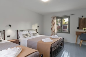 A bedroom with two beds, a desk, and a chair.