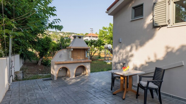 An outdoor patio with a barbecue grill, a table, and two chairs.