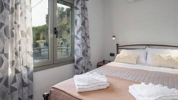 Una habitación de hotel con cama, ventana con cortinas, mesita de noche y equipo de aire acondicionado.