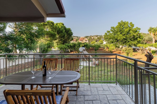 A balcony with a table and chairs, a bottle, and glasses.