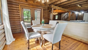 Ein rustikales Holzblockhaus-Interieur mit Essbereich, inklusive rundem Tisch und vier Stühlen.
