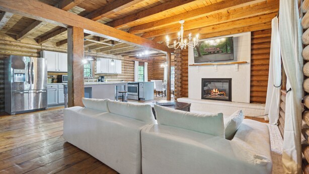 Ein Holzhaus-Interieur mit Holzboden, weißem Sofa, Kamin und Küchenbereich.