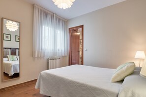 A bedroom with a bed, a bedside lamp, a window with curtains, a door, and a mirror on the wall. - Casa María - Rural House in Molinaseca, Camino de Santiago, El Bierzo (Molinaseca)