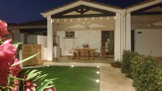 Un espace extérieur abrité, équipé d’une table et de chaises, d’un hamac et d’un petit jardin.