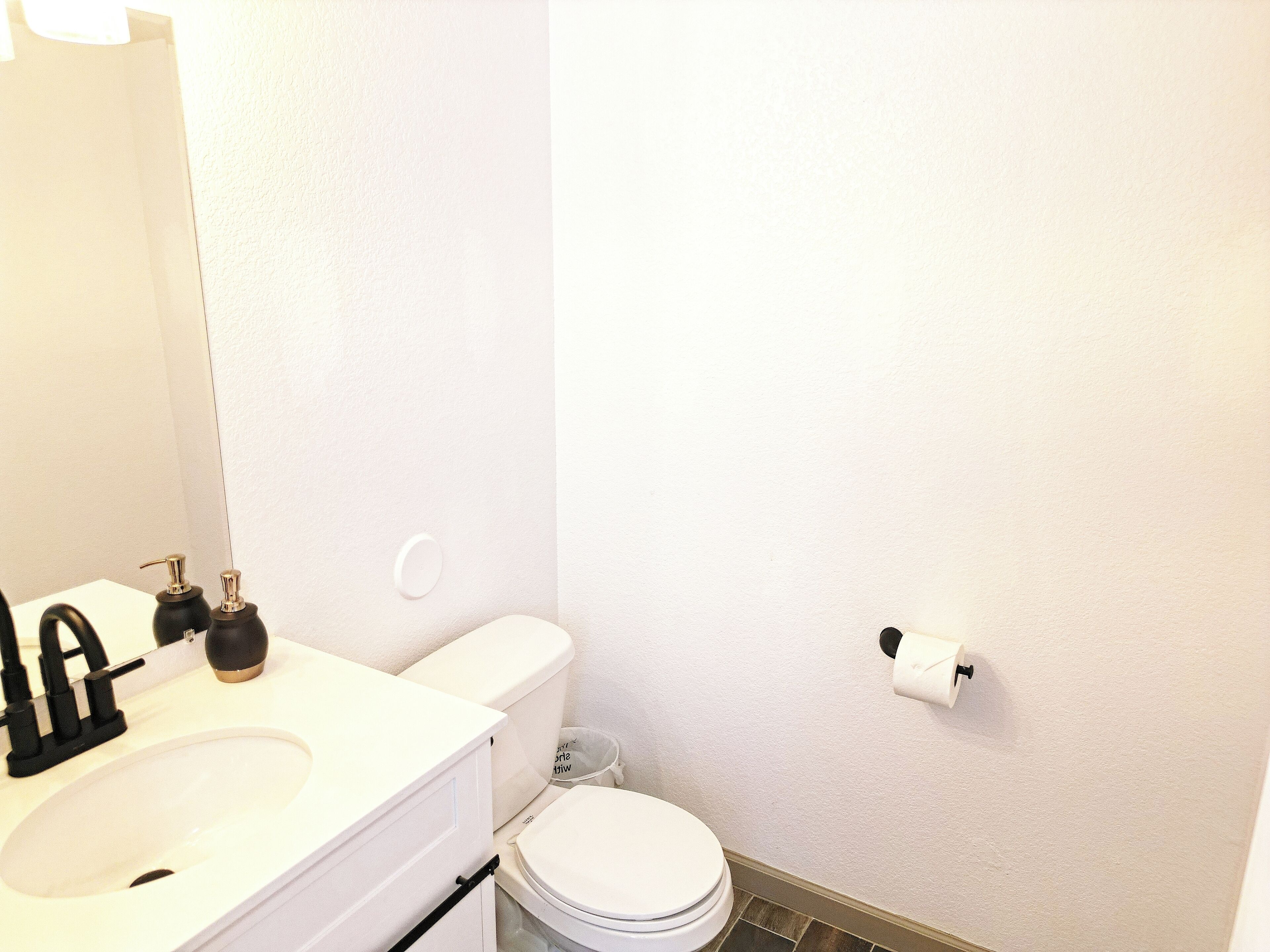 Une salle de bain avec un lavabo blanc, des toilettes et un miroir.