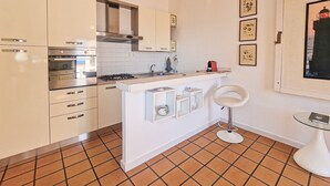 Een keuken met witte kastjes, een fornuis en een klein eiland met planken.