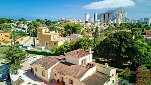 Zona residencial amb una piscina, un edifici petit amb teulada ceràmica i una muntanya al fons.