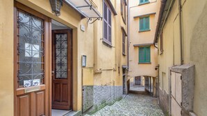 A narrow alleyway with cobblestone pavement, wooden doors with metal grilles, and buildings with green shutters. - Studio Apartment 'Kella's Holiday Home' with Balcony, Wi-Fi and Air Conditioning (Bellagio)