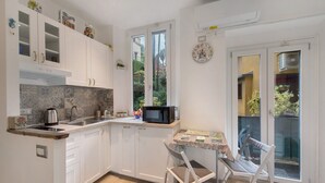 A compact kitchen with white cabinets, a microwave, and a small table with chairs. - Studio Apartment 'Kella's Holiday Home' with Balcony, Wi-Fi and Air Conditioning (Bellagio)