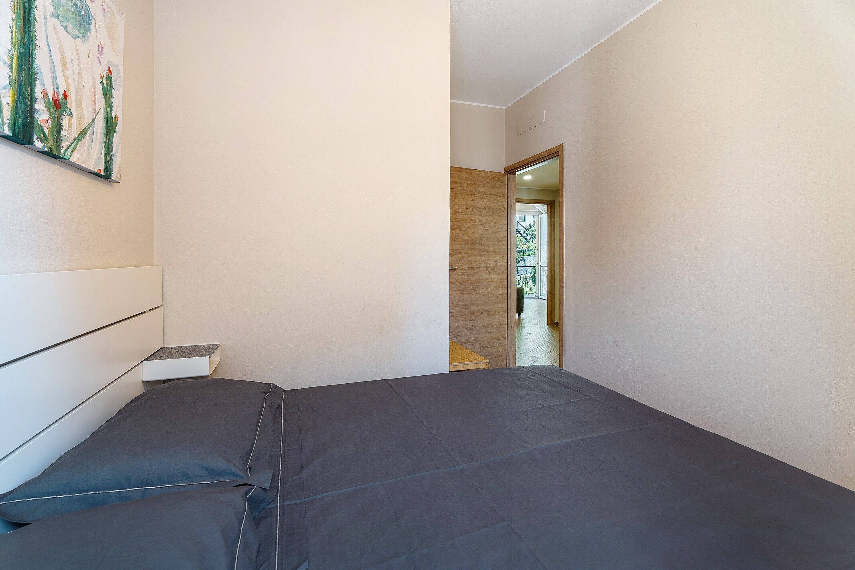 Ein Schlafzimmer mit einem Bett, einem Nachttisch und einem Bild an der Wand.