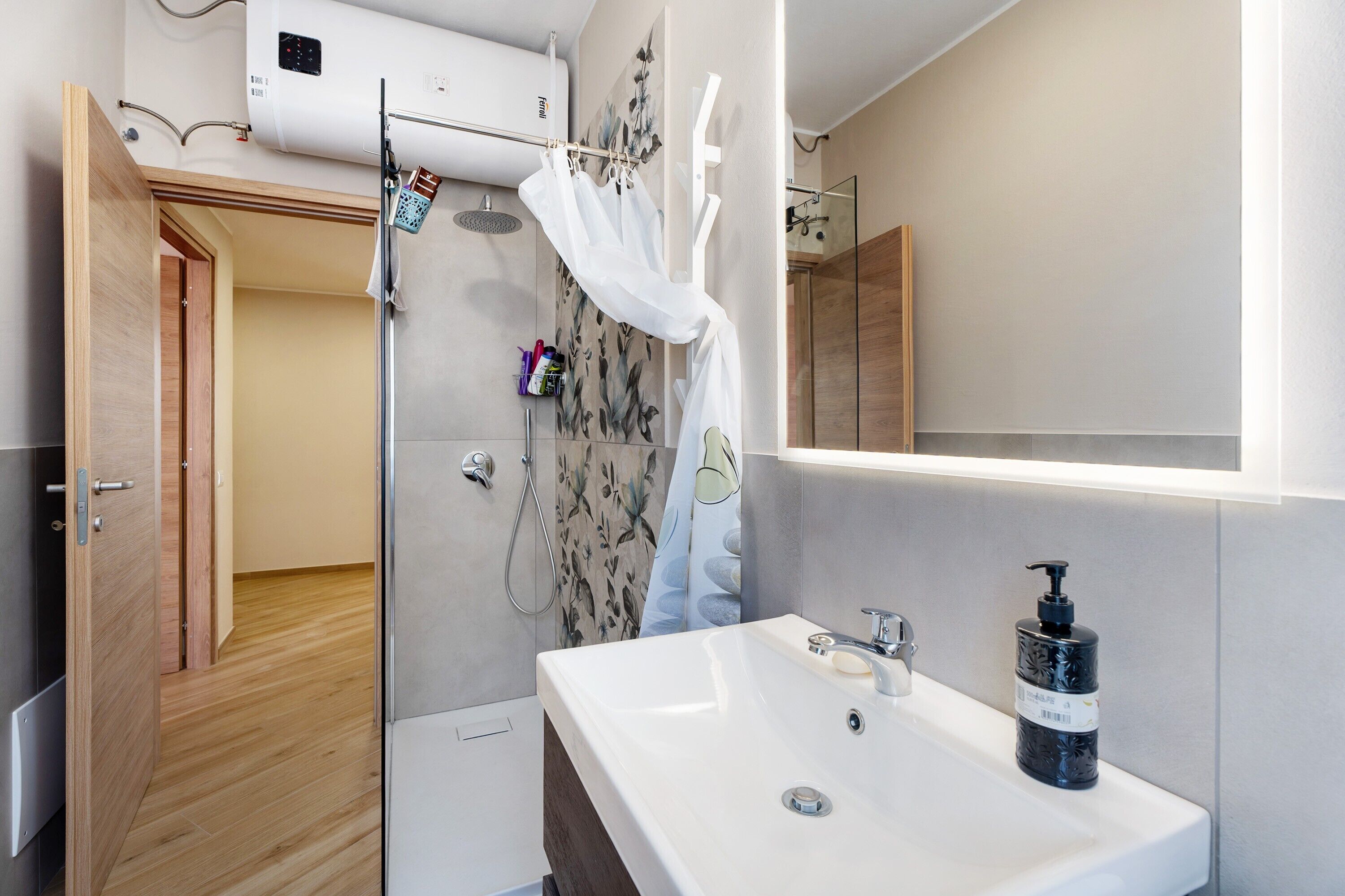 Un baño moderno con ducha, lavabo y espejo.