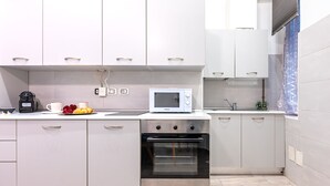 A modern kitchen with white cabinets, a microwave, an oven, and a coffee maker.