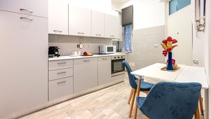 A modern kitchen with white cabinets, a microwave, a coffee maker, and a dining area with a table and chairs.