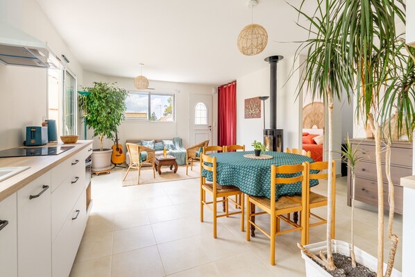 A spacious living area with a dining table, chairs, a sofa, and a kitchen area with cabinets and a stove.