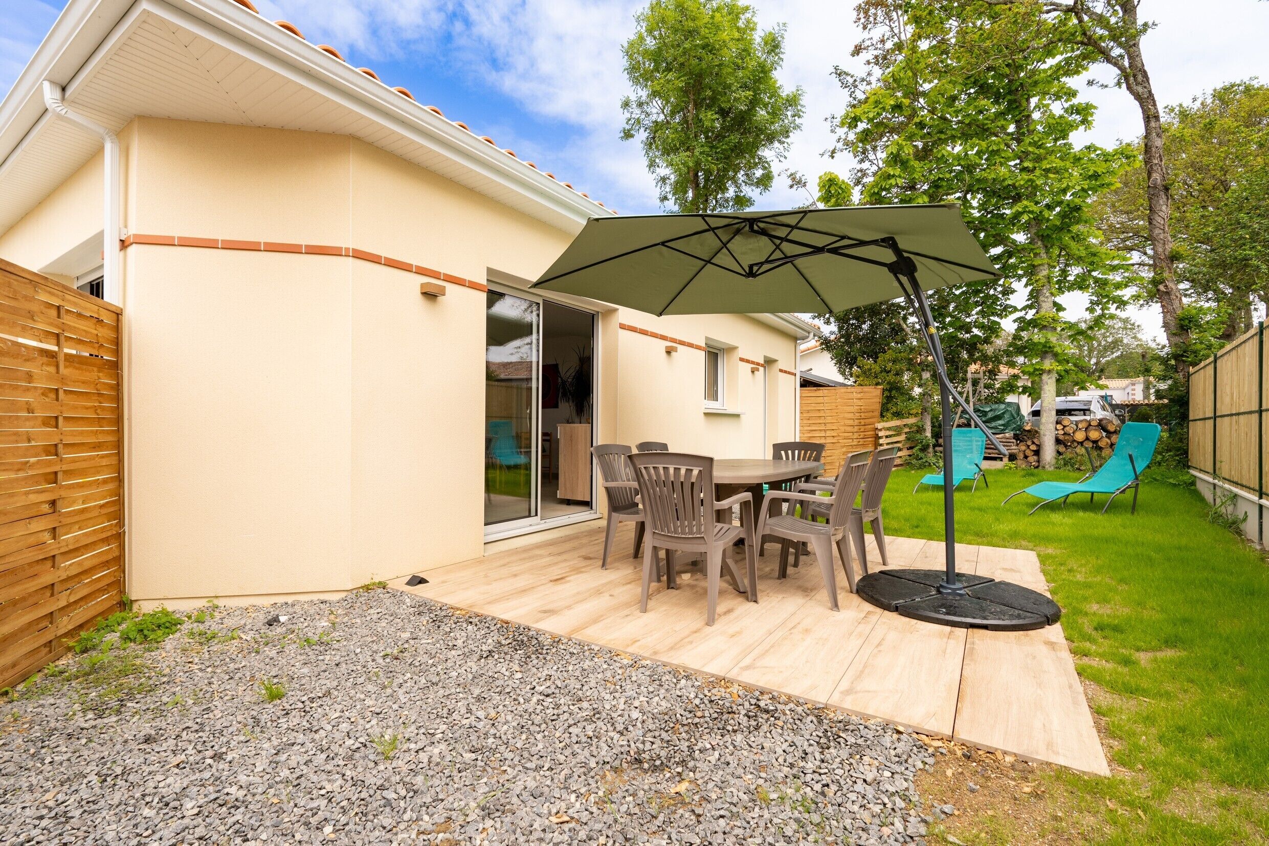 Eine Terrasse mit Tisch und Stühlen, einem überdachten Sonnenschirm und einem Holzdeck.