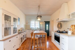 A kitchen with wooden cabinets, a dining table, and a stove.