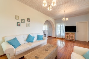 A living room with a sofa, coffee table, TV, and decorative items on the wall.