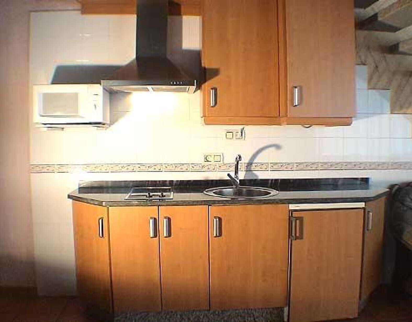 Une cuisine avec des meubles en bois, un four à micro-ondes et une cuisinière à gaz.