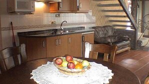 Een keuken met houten kastjes, een magnetron en een fruitmand op de tafel.