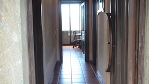 A hallway with a tiled floor, a door with a dark frame, and a window at the end. - Country House 'Cuarto Del Ama' with Mountain Views, Private Garden and Wi-Fi (Rozas De Sanabria)