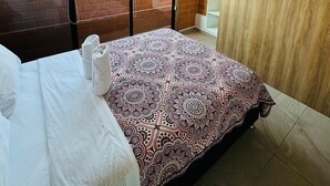 Une chambre dotée d’un grand lit, d’un ventilateur de plafond, d’une vue sur la ville grâce à une grande fenêtre et d’une armoire en bois.