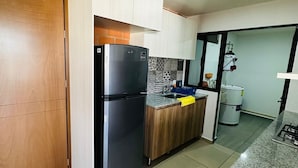Une cuisine moderne avec un réfrigérateur noir, des armoires en bois et un plan de travail en granit.