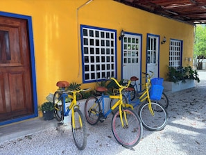 Guests can park their bicycles in front of this charming building, which features a wooden door and window boxes with plants.