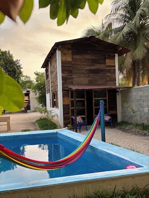 Une maison en bois avec une piscine et un hamac.