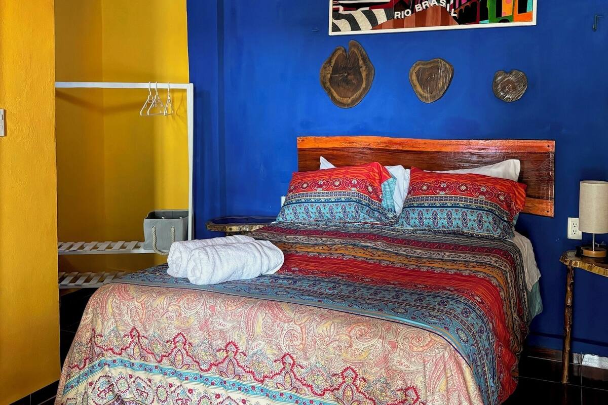 A room with a bed, a painting, and a wooden headboard.