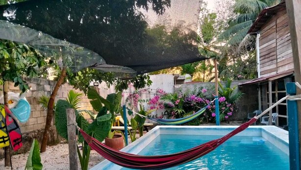 A swimming pool with a hammock, surrounded by plants and a shaded area. - Un Toque de Brazil, Bacalar (Bacalar)