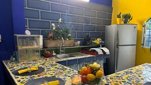 A kitchen with a tiled backsplash, a refrigerator, and a fruit bowl on the counter. - Un Toque de Brazil, Bacalar (Bacalar)