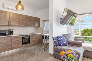 Une cuisine moderne avec des meubles en bois, un four encastré et un coin repas comprenant une table et des chaises.