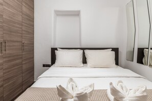 Une chambre d’hôtel avec un lit, une armoire, un miroir et des serviettes sur le lit.