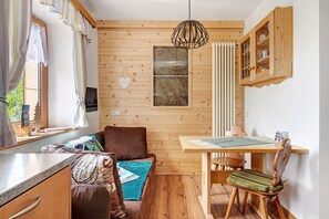 L’intérieur d’une cabane en bois comprend une table à manger, un banc rembourré, un luminaire suspendu et un meuble de rangement.