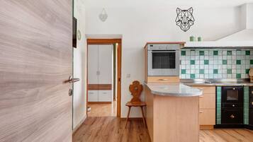 Cuina amb armaris de fusta, respatller de rajoles i forn integrat.
