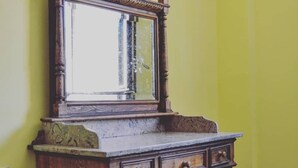 Un meuble en bois avec un miroir, des tiroirs et un plan de travail en marbre, le tout adossé à un mur jaune.
