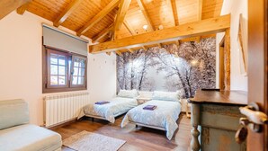 Une chambre avec deux lits, un plafond en bois, un radiateur, une fenêtre et une peinture murale.