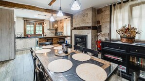 Une cuisine moderne dotée d’un grand îlot central, de murs en pierre et de luminaires suspendus.