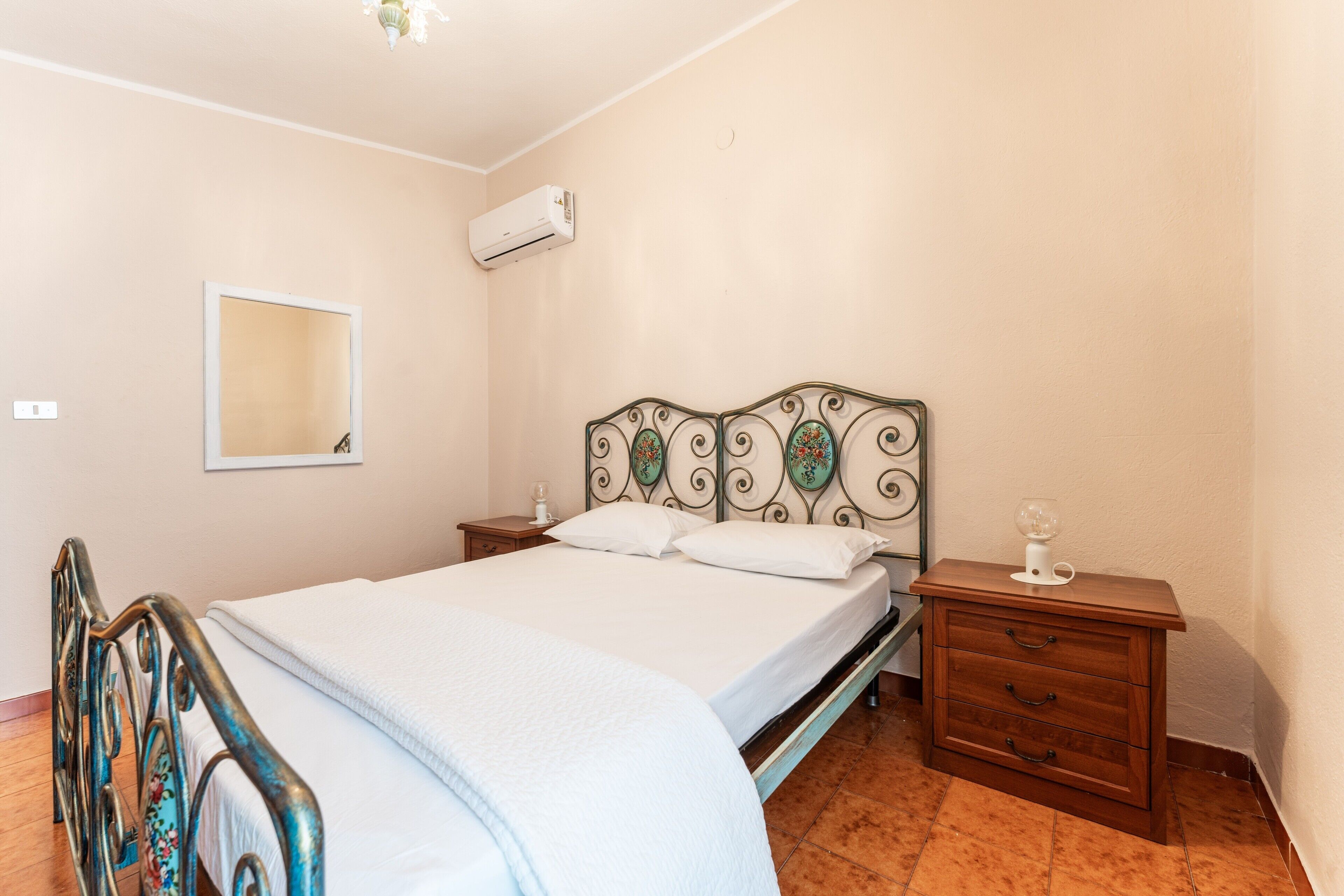 Une chambre à coucher comprenant un lit, une table de chevet, une commode, un miroir et un appareil de climatisation.