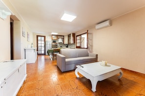 A spacious living area with a sofa, coffee table, and kitchen in the background.