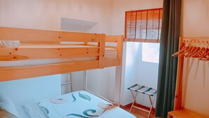 Una stanza con un letto a castello, un tavolino, una lampada a sospensione e una finestra con persiane.