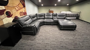 Habitación con sofá modular, cama, piso alfombrado y un mural en la pared con motivos musicales.