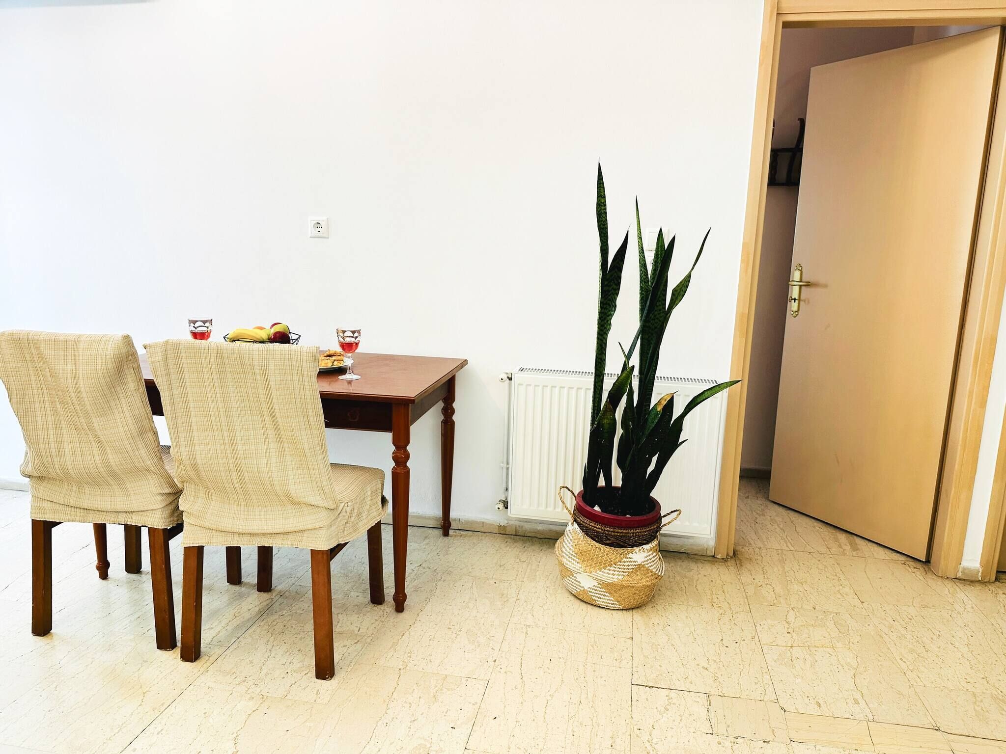 Un coin repas comprenant une table, des chaises, une plante en pot et un radiateur.