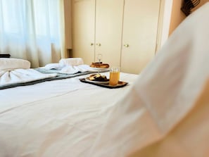 Un letto rifatto con cura, un vassoio con cibo e bevande, un asciugamano e un tavolino di legno.