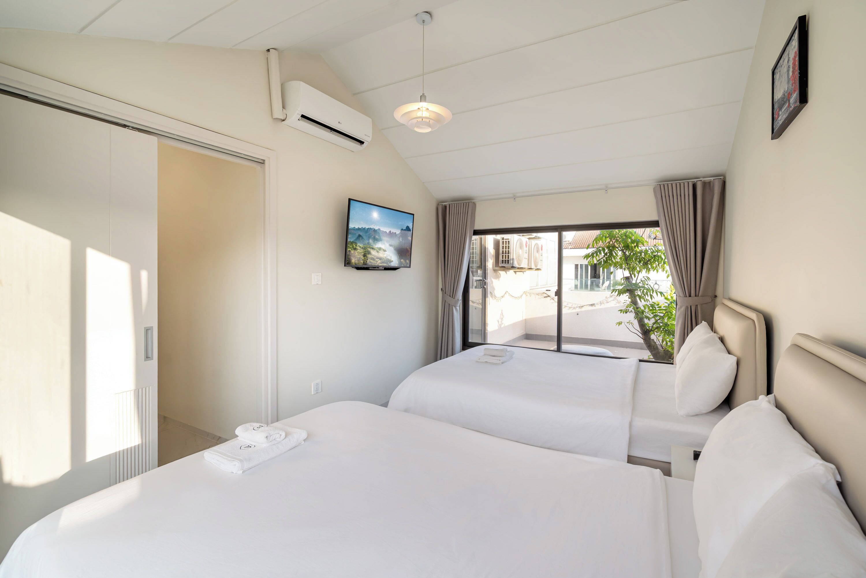 Une chambre d’hôtel avec deux lits, une télévision et une vue sur l’extérieur.