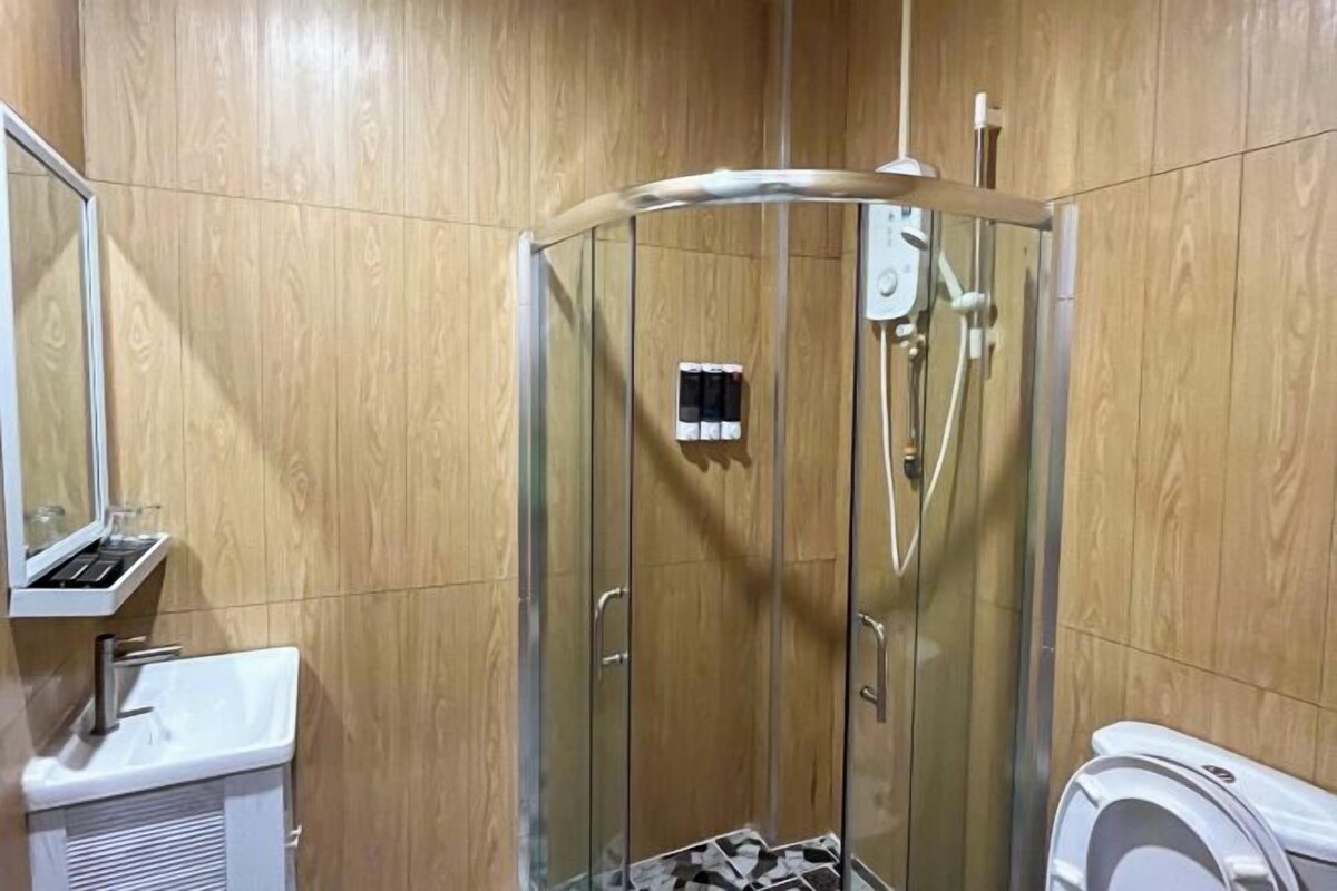 Un baño con ducha de vidrio, lavamanos y retrete.