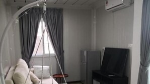 A living room with a hanging chair, a sofa, a flat-screen TV, a refrigerator, and a striped rug. - Titiwangsa Cabin Retreats by uBook (Kuala Lumpur)