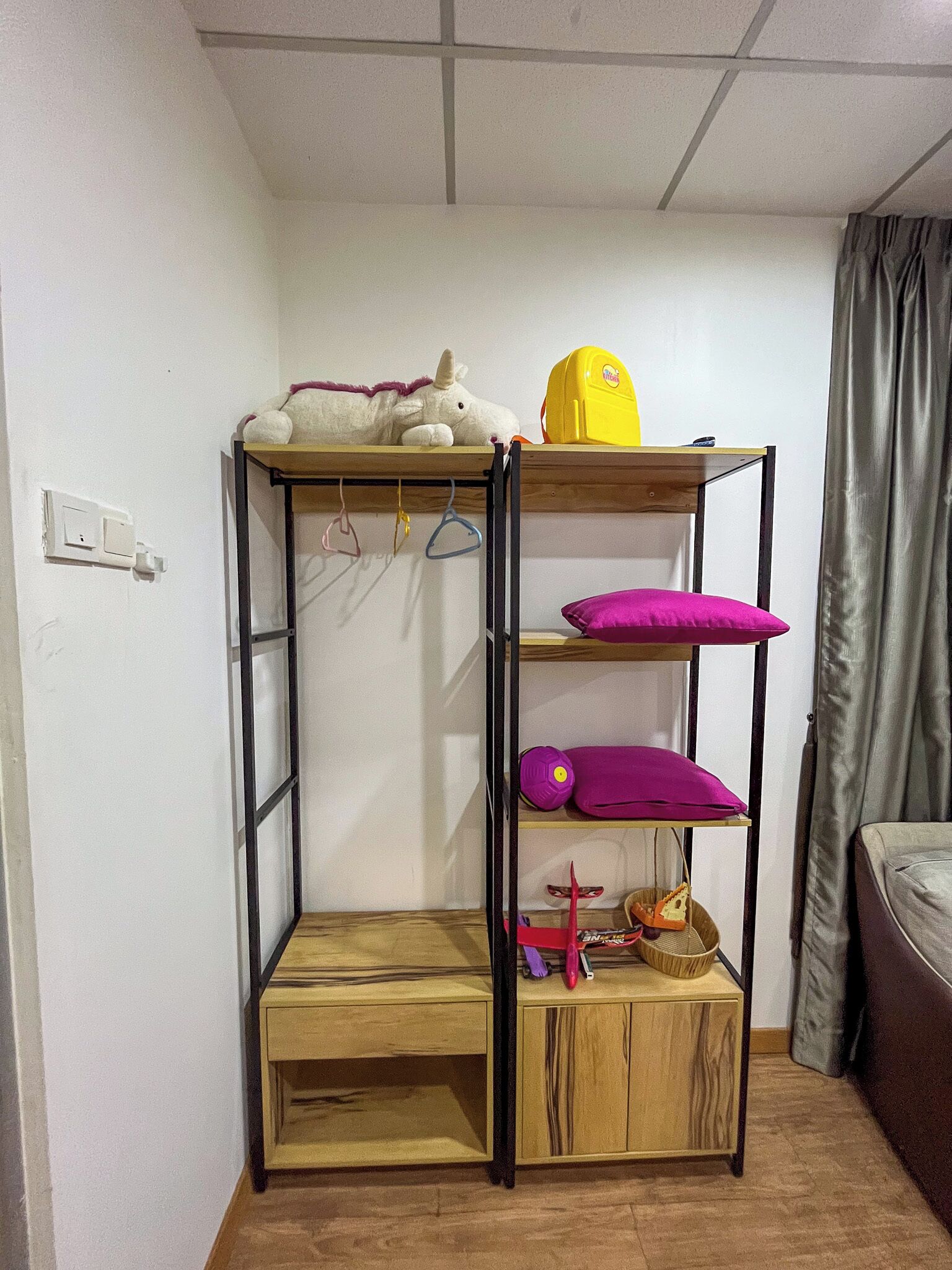 A compact room with a bunk bed, a small table, and a shelf with various items.