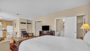 Habitación de hotel con una cama grande, un escritorio, una silla, un televisor y un baño visible a través de una puerta abierta.