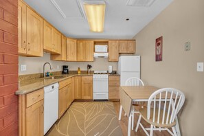 A compact kitchen with wooden cabinets, a built-in microwave, a stove, and a refrigerator. - Charming Studio in the Heart of Park City! (Park City)